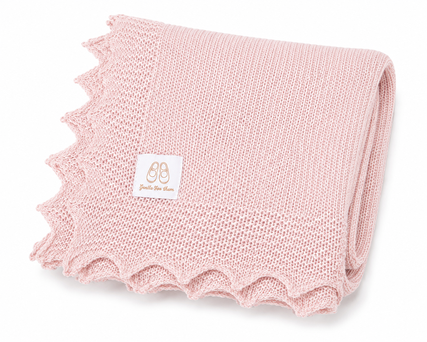 A folded light pink knit baby blanket with a scalloped edge and a small white brand label, photographed on a clean white background.